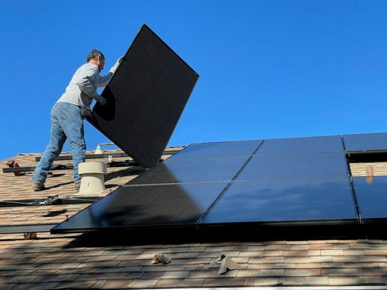 Solar Panels - man in white dress shirt and blue denim jeans sitting on white and black solar panel