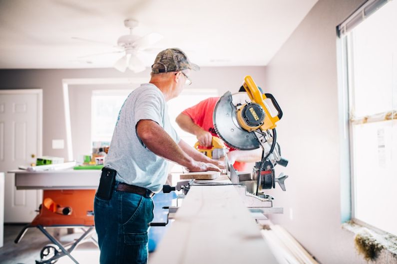 DIY Plumbing - man standing infront of miter saw