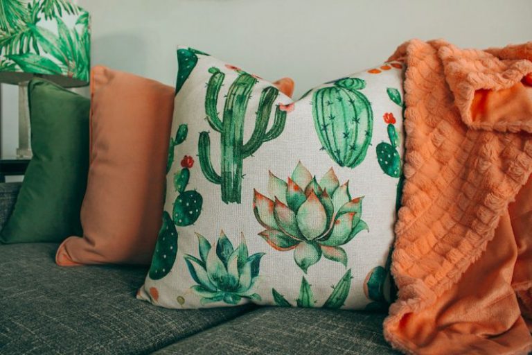 Throw Pillows - three green, orange, and white throw pillows on sofa