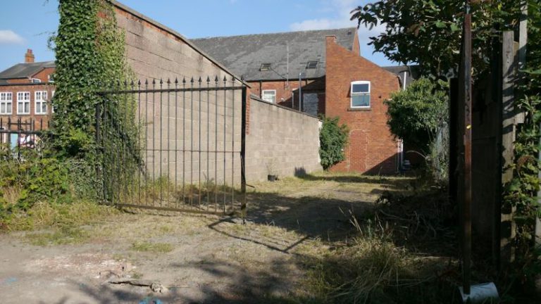 Backyard Privacy - an old brick building with a gate in front of it